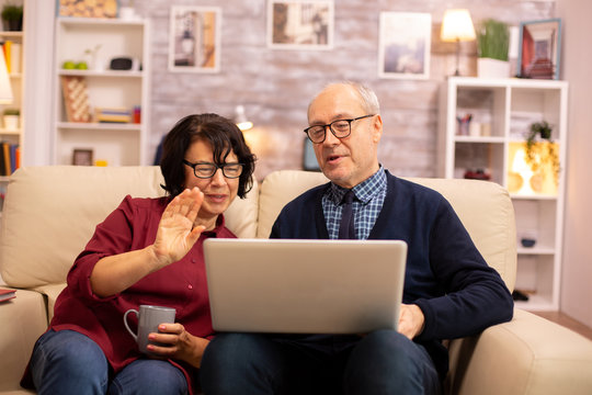 Elderly old couple using modern laptop to chat with their grandson