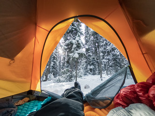Traveler stretching the legs in tent on snowy pine forest at Yoho national park