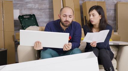 Fototapeta na wymiar Girlfriend and boyfriend assembling furniture in their new apartment