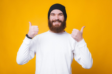 Photo of trendy bearded man smiling and showing thumbs up