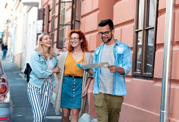 Group of tourists enjoying on vacation, young friends having fun walking on city street during the day.