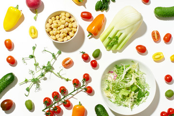 Healthy salad ingredients on white background in hard sun light with harsh shadows. Vegan meal. Pattern isolated