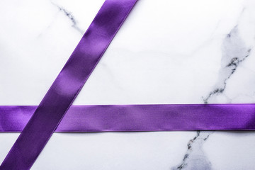 Purple silk ribbon and bow on luxury marble background, holiday flatlay backdrop