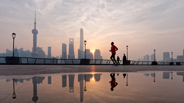 Silhouette morning runner running at famous bund zone with sun rising shanghai city background.