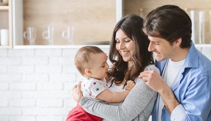 Happy parents with their adorable baby son in kitchen