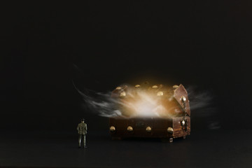 Business concept. A man stands in front of an old treasure chest with mysterious shiny light and smoke. An idea of success, wealth and challenge
