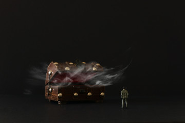 Business concept. A man stands in front of an old treasure chest with mysterious smoke. An idea of success, wealth and challenge