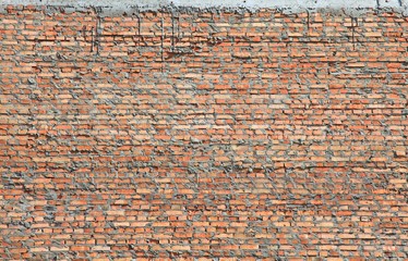 Red bricks wall texture and background. The fragment of bad and dirty bricklaying with cement smeared bricks. Сonstruction of a new multistory building. Construction site