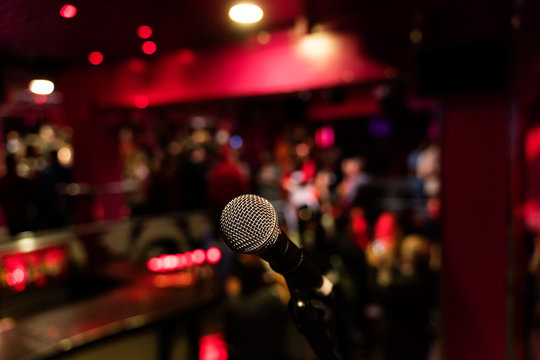 microphone on a stand up comedy stage with colorful bokeh , high contrast image.