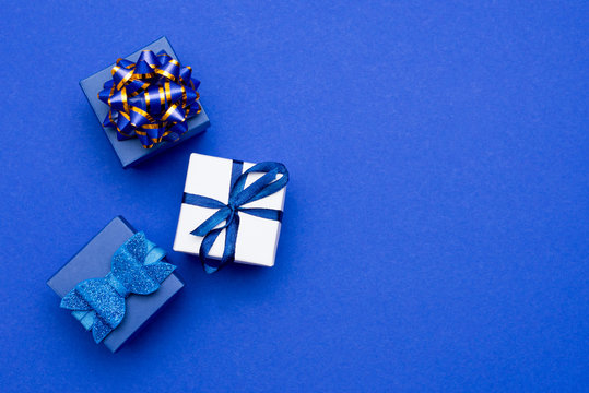 Group of gift boxes with silver ribbons on classic blue background with copy space