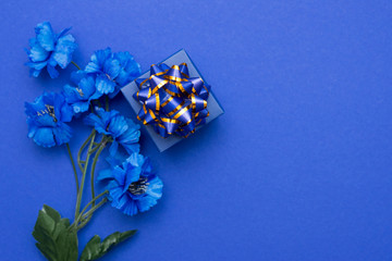 Flower Bouquet and elegant gift box. Blue Flowers on classic blue background. Top view, Flat lay, Copy Space