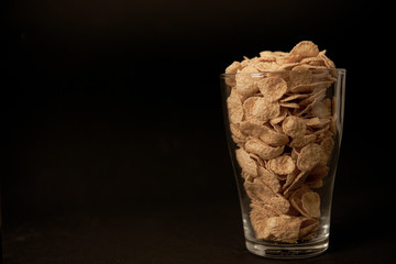 cornflakes in a transparent glass against a black background