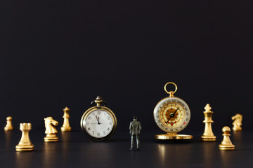 Image of chess game. Businessman looking at vintage clock, compass and pawns, competition, strategy, leadership and success concept