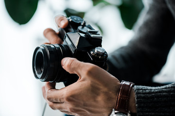cropped view of bi-racial man holding digital camera in apartment