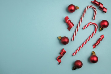 Christmas winter composition. Red balls with candy canes on blue background. Top view, flat lay