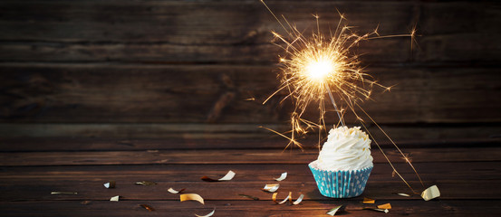 birthday cake with sparkler on old wooden background