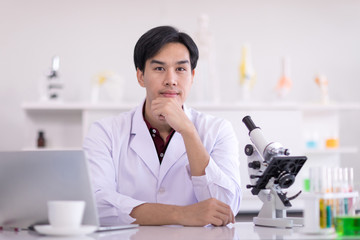 Asian scientists wear white robes, look at cameras in the laboratory