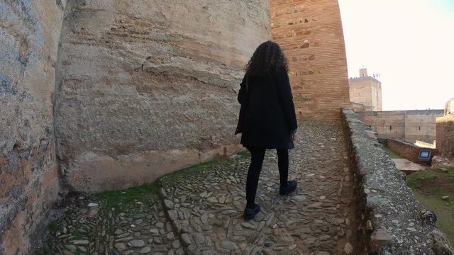 Granada, Andalusia, Spain. December 15-2019: Woman walking through the Alcazaba in the Alhambra Palace. 4K shot.