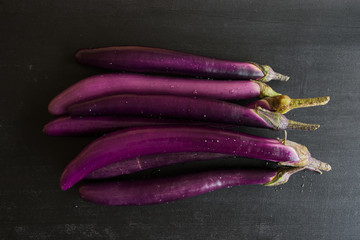 Fresh japanese eggplants on dark background, top view.