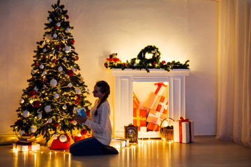 woman decorates the Christmas tree Garland lights new year holiday gifts white home decor