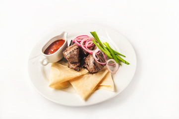 Skewers with sauce in a restaurant close-up. Skewers with onions and pita bread on a white plate and copy space.