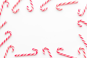 Christmas candies frame - cane with red and white stripes - on white background top-down copy space