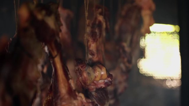 Ham and bacon hanging and drying in smokehouse on traditional way on blue smoke.  The sunrays pierce through the blue smoke.