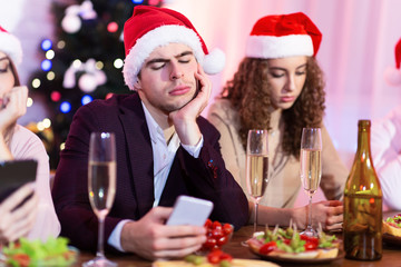 Bored Couple Using Phones During New Year Celebration Sitting Indoor