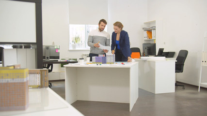 Man and woman discuss a project of houses in the office