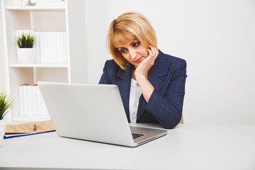 Blond woman sitting at the desk in office and working