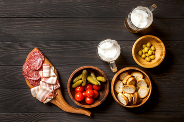 Ingredients for making tapas or bruschetta. Crusty bread, ham ,  tomatoes, olives on plates over dark texture background. Top view