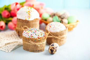 Fototapeta na wymiar Easter orthodox sweet cakes, kulich and colorful quail eggs with pink tulips. Holidays Easter concept. Selective focus