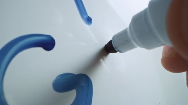 Macro Follow Shot of a Blue Marker Pen Being Held with a Hand. Person Writing on a Whiteboard with Graphs and Business Plans. Pencil is Connected to the Camera. Gripped Shot. Writing "Grow".