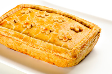 Salty pie with a crispy golden-brown crust, ready to eat, on a white plate