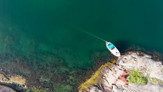 Top down aerial drone view of rocky coast and single boat docket in Bohuslan, Sweden