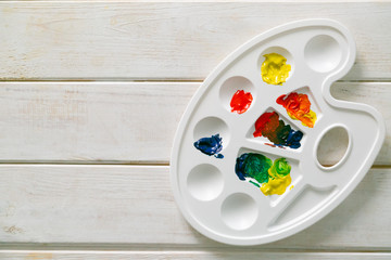 Art concept - colour wheel, gouache paints, brush and palette on wood background, copy space top...