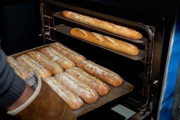 Taking out of the oven, trays of freshly baked bread in a bakery in Madrid, Spain