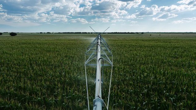 Creative point of view timelapse on top of centre pivot irrigation system, late afternoon, sun set, with cumulous clouds while sprinklers are on to water corn, South Africa.