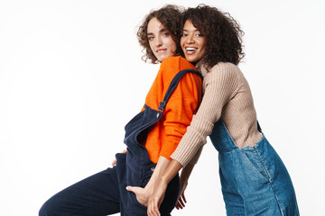 Portrait of joyful multinational women looking at camera and hugging