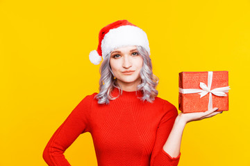 Santa girl holding big golden present and smiling