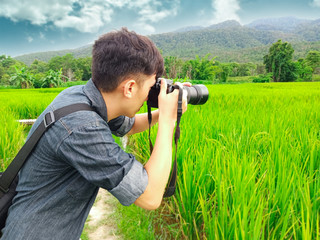 Young man taking photographs with digital camera at field paddy. Travel and active lifestyle concept