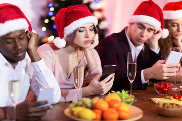 Bored Friends Using Mobile Phones During Christmas Party Sitting Indoor