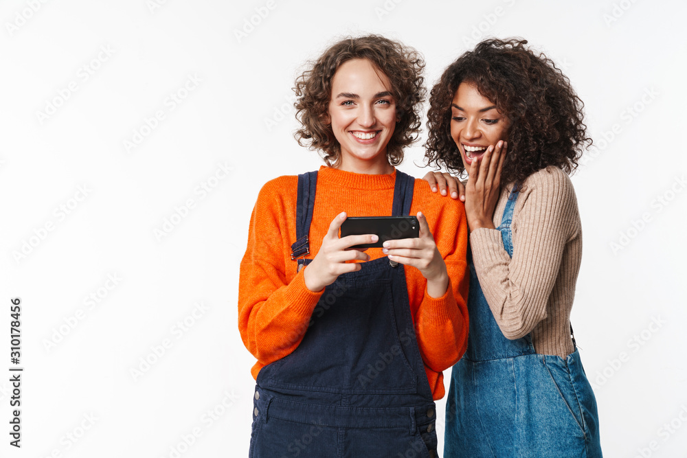 Canvas Prints multiracial girls friends in denim jumpsuits using mobile phone.