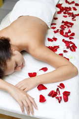 Obraz na płótnie Canvas Woman resting in beauty salon with rose petals