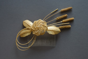 Ornamental hair comb with straw flowers on a gray background