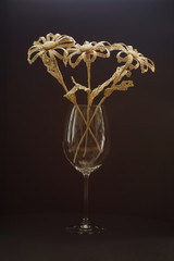 A glass vase with a bouquet of flowers made from straw on a dark background