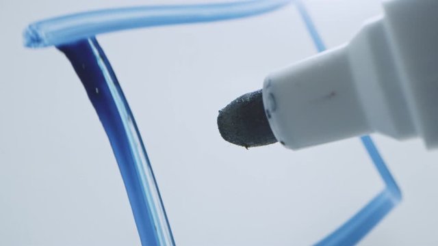 Macro Follow Shot of a Blue Marker Pen Being Held with a Hand. Person Drawing a Box on a Whiteboard and Inserting a Tick Mark. Pencil is Connected to the Camera. Gripped Shot.