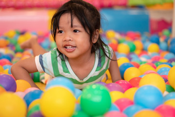 Fototapeta na wymiar Happy Asian girl (4 years olds) playing little colorful balls in pool ball. The concept of playing is the best learning for children.