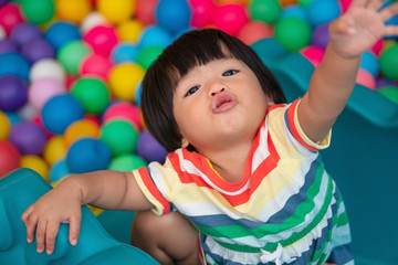 Happy Asian girl (one and half years olds) playing little colorful balls in pool ball. The concept...