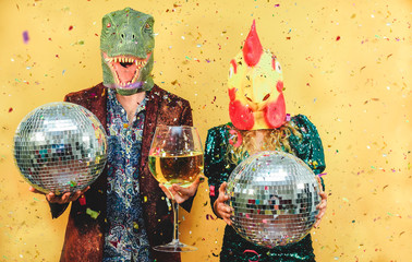 Crazy young couple having fun for new year's eve party wearing t-rex and chicken mask - Fashion...
